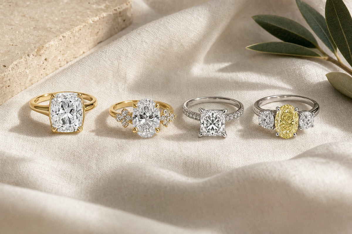 Four engagement rings in cushion, oval, princess and three-stone oval styles on linen